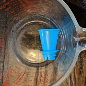 A water pillow funnel in a measuring cup.