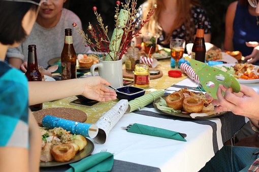 Photo of people gathered around a crowded table eating a meal at a party.