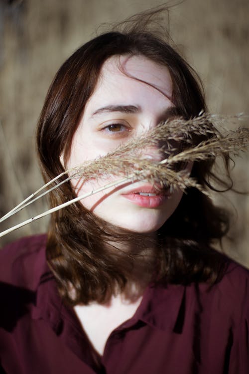 Sleepy woman with grass near face.