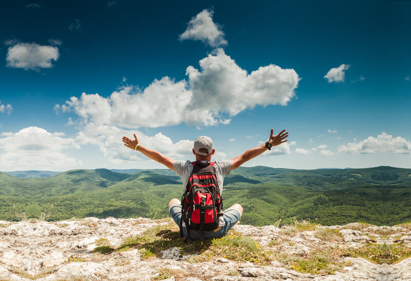 a man sitting at a summit, looking at clouds