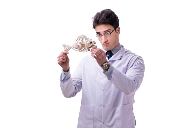 Man wearing laboratory smock staring wide-eyed at a fish fossil.