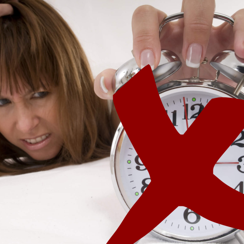 Sleepy woman reaching for an crossed out alarm clock.