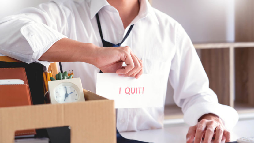 Man holding paper with the words "I quit" written on it.