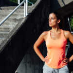 Sweaty woman wearing orange tank top who has just worked out.