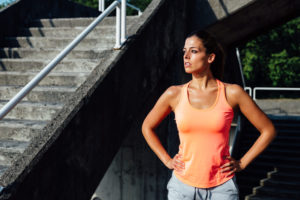 Sweaty woman wearing orange tank top who has just worked out.